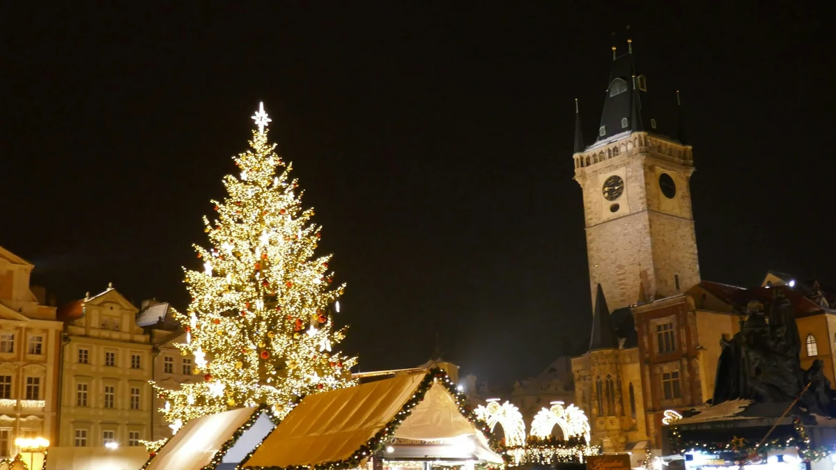 Decorated Christmas tree and market stalls lit up at night on Old Town Square in Prague