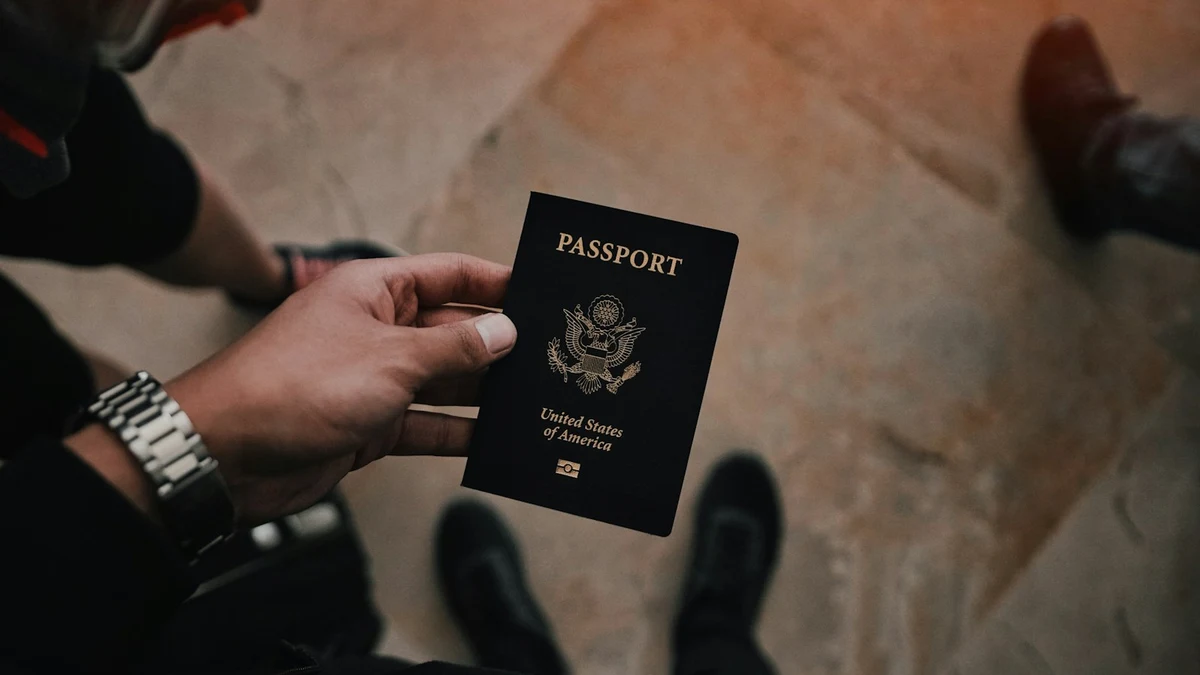 A traveller holding a passport, seen from above on a stone floor