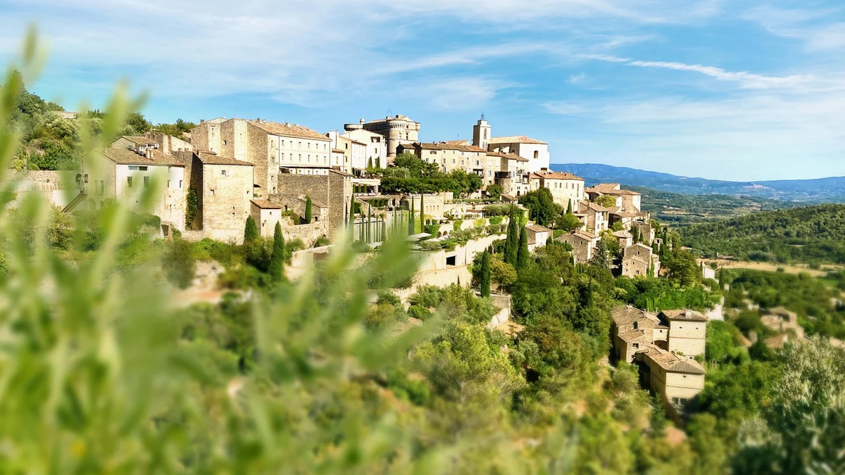 A hilltop village in Provence with stone houses, cypresses and open countryside behind it