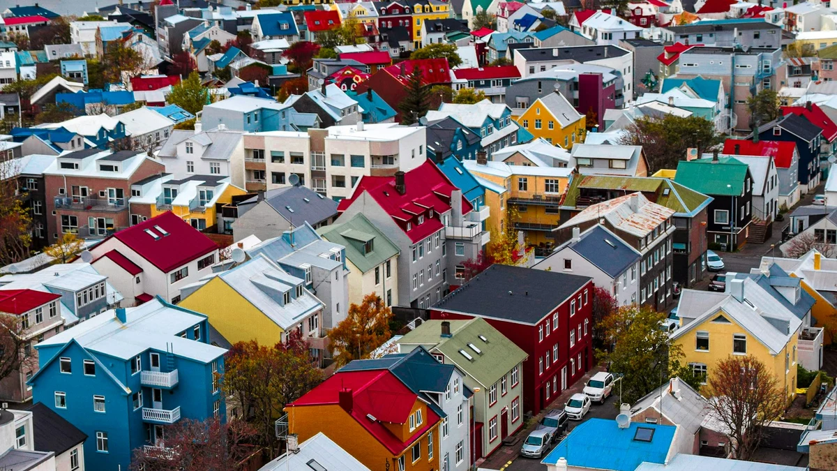 Colourful houses and red, blue and green roofs of central Reykjav&iacute;k seen from above, with autumn trees between them