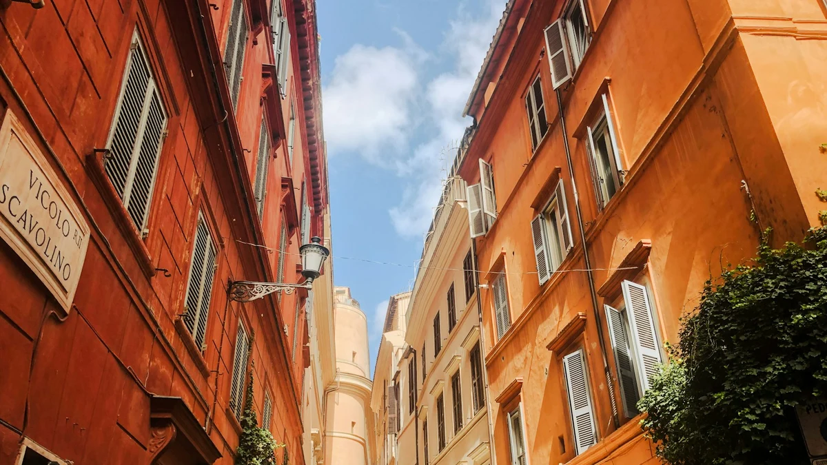 Sunlit terracotta and ochre buildings lining a narrow street in Rome