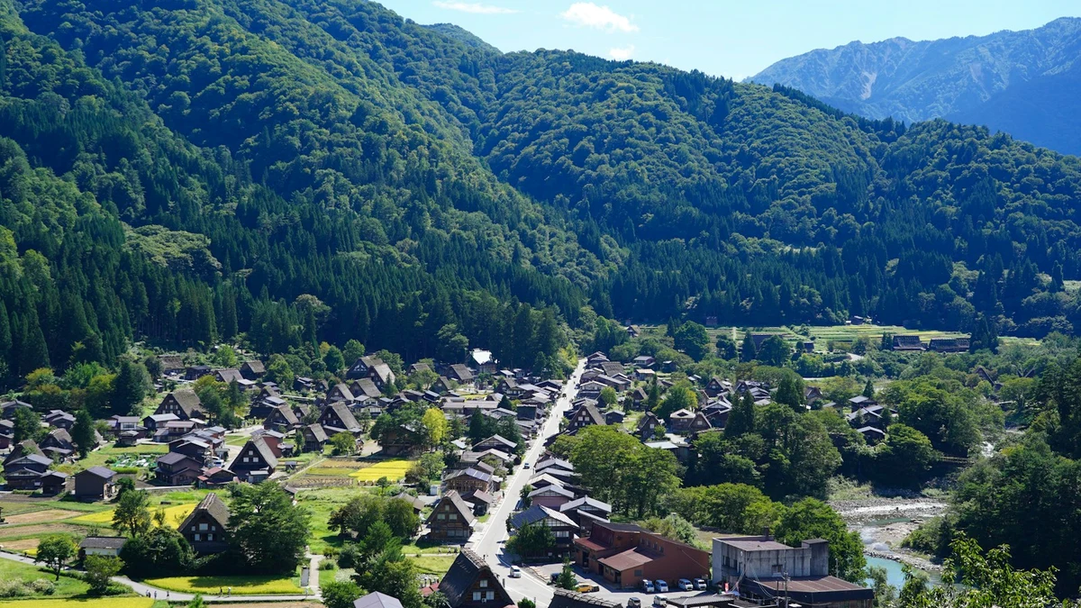 A mountain valley in central Japan with a village of steep-roofed houses, forest and a river