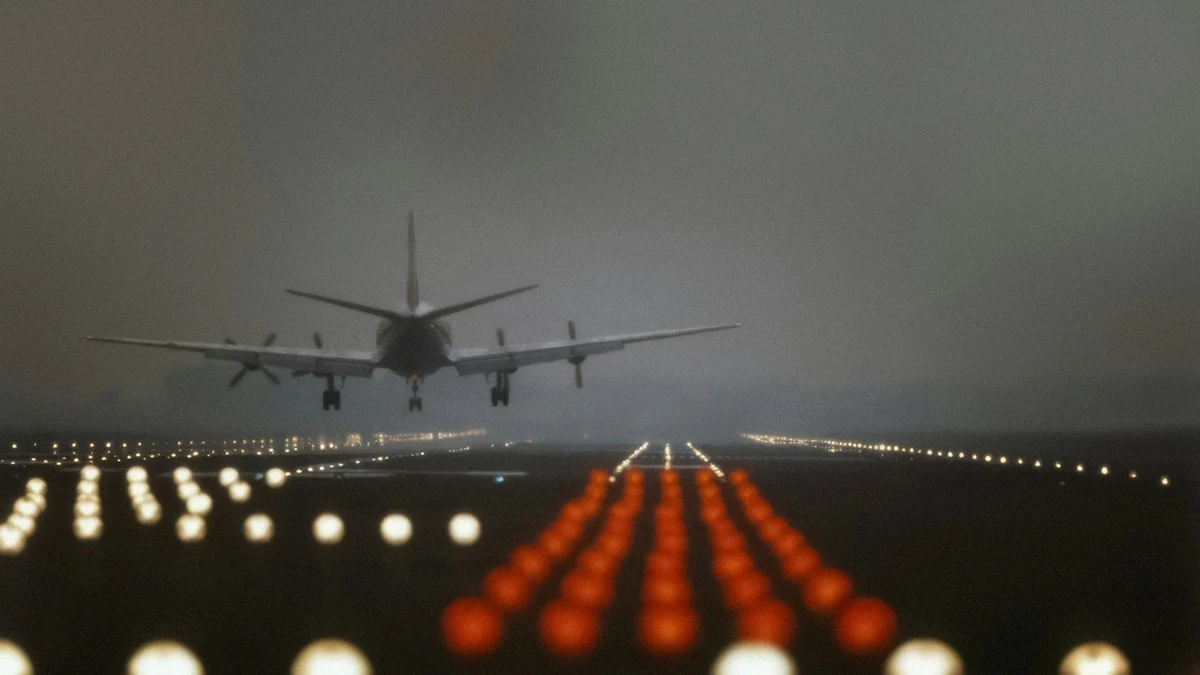 An aircraft on final approach over a double row of runway lights at dusk