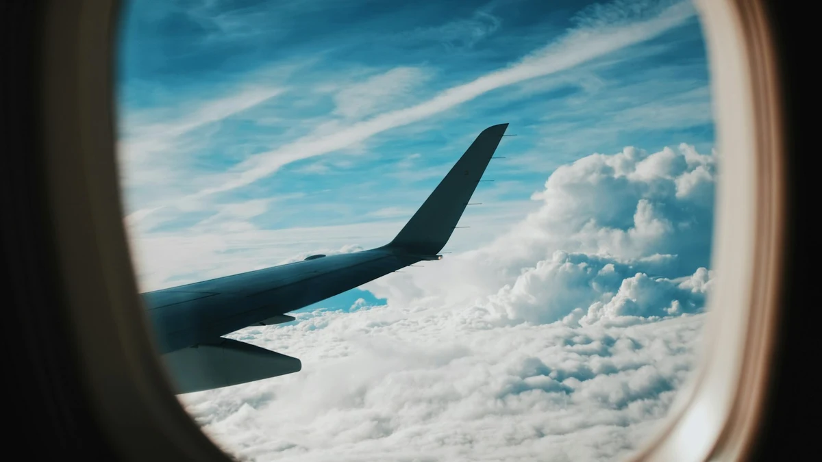 A wing and layered cloud seen through an aircraft cabin window