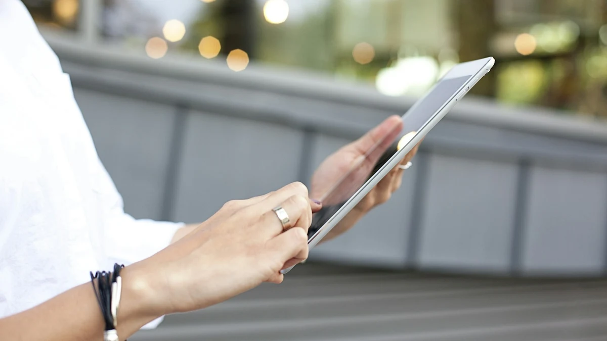 Hands holding a tablet outdoors on a city street