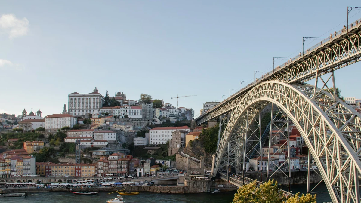 The Dom Luis I bridge over the Douro with the terraced Ribeira waterfront behind it in evening light