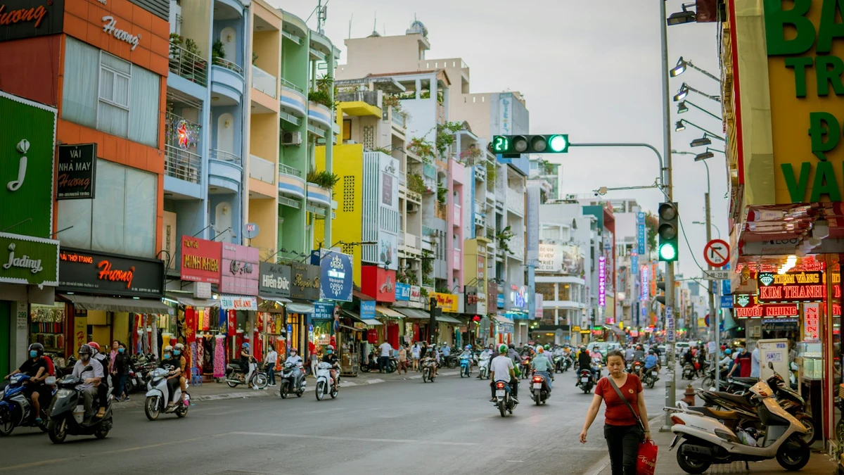 Motorbikes and painted shophouses along a wide Ho Chi Minh City street