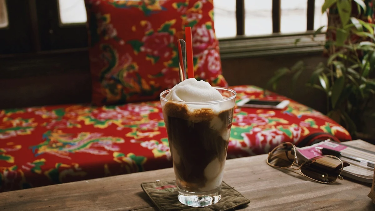 A Vietnamese iced coffee on a wooden café table beside an open window
